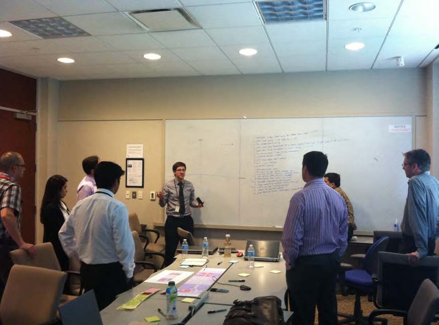 Russell Cornwell standing in front of a whiteboard and gesturing to a roomful of GE Healthcare personnel